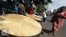 Seorang warga tampak melintas di depan penjualan bedug di kawasan Tanah Abang, Jakarta, Kamis,(16/7/2015). Harga bedug berkisar Rp.200-700 Ribu tergantung ukuran. (Liputan6.com/Helmi Afandi)