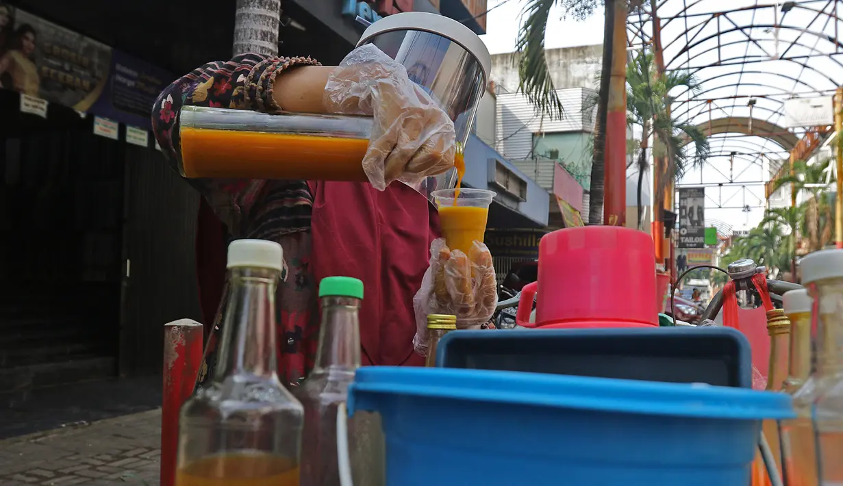Tidar (46), melayani pembeli di Pasar Baru, Jakarta, Kamis (11/06/2020). Penjual jamu tradisional keliling ini tampak mematuhi protokol kesehatan pencegahan COVID-19 dengan mengenakan masker, face shield, dan sarung tangan dalam melayani pelanggan setianya. (Liputan6.com/Herman Zakharia)