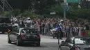 Kerumunan orang menyaksikan iring-iringan mobil yang diyakini membawa pemimpin Korea Utara Kim Jong-un di Orchard Road menuju St Regis Hotel, Singapura, Minggu (10/6). Kedatangan Kim menjelang pertemuan bersejarah dengan Donald Trump. (AP/Joseph Nair)
