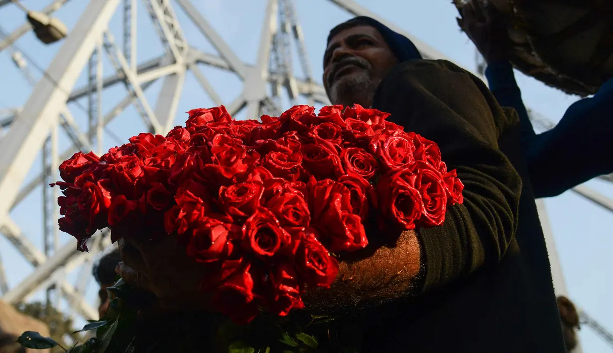 Pedagang merapihkan bunga mawar saat mereka menunggu pelanggan di pasar bunga grosir di Kolkata, India (7/2). Jelang perayaan hari Valentine, bunga mawar banyak diburu dari tanggal 7 Februari dengan ditandai dengan Rose Day. (AFP Photo/Dibyangshu Sarkar)
