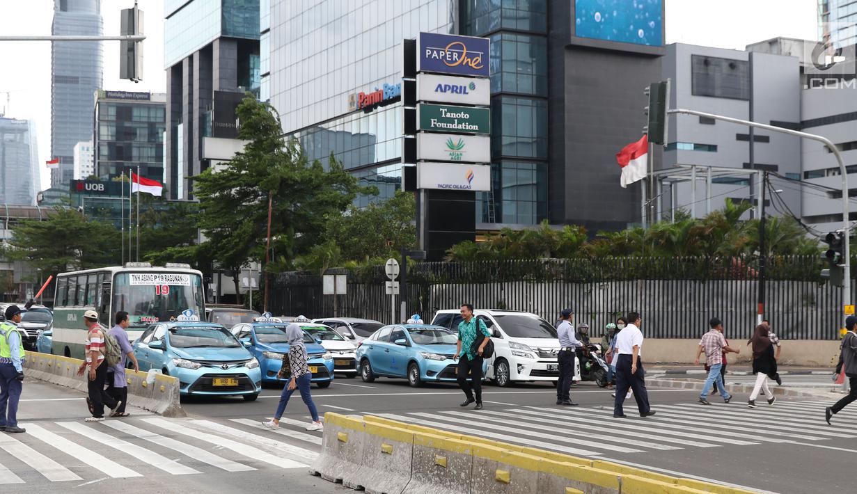 Warga menyebrang jalan Sudirman di kawasan Tosari, Jakarta, Jumat (14/12). Penggunaan pelican crossing di kawasan ini menggantikan fungsi Jembatan Penyebrangan Orang (JPO) Tosari yang akan dibongkar. (Liputan6.com/Helmi Fithriansyah)