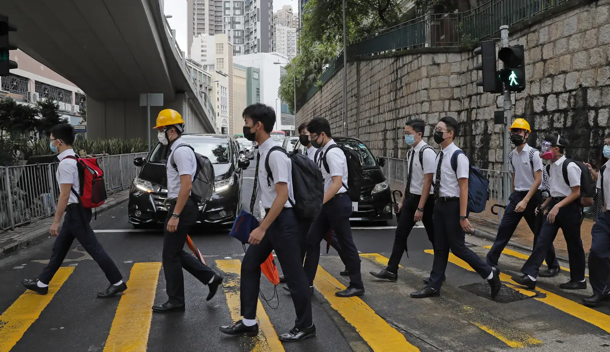 Para siswa sekolah mengenakan topeng dan helm berjalan di luar St. Paul's College selama protes di Hong Kong, Selasa (3/9/2019). Puluhan ribu siswa di Hong Kong mogok sekolah di hari pertama tahun ajaran baru. (AP Photo/Kin Cheung)
