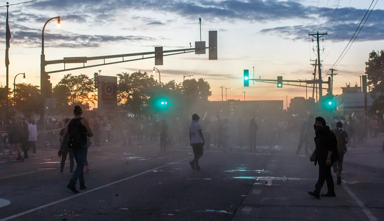 Demonstran bentrok dengan polisi saat unjuk rasa atas kematian George Floyd oleh polisi di luar Third Police Precinct, Minneapolis, Minnesota, Amerika Serikat, Rabu (27/5/2020). Pria kulit hitam, George Floyd, meninggal karena kehabisan napas setelah lehernya diduduki oleh polisi. (Kerem Yucel/AFP)