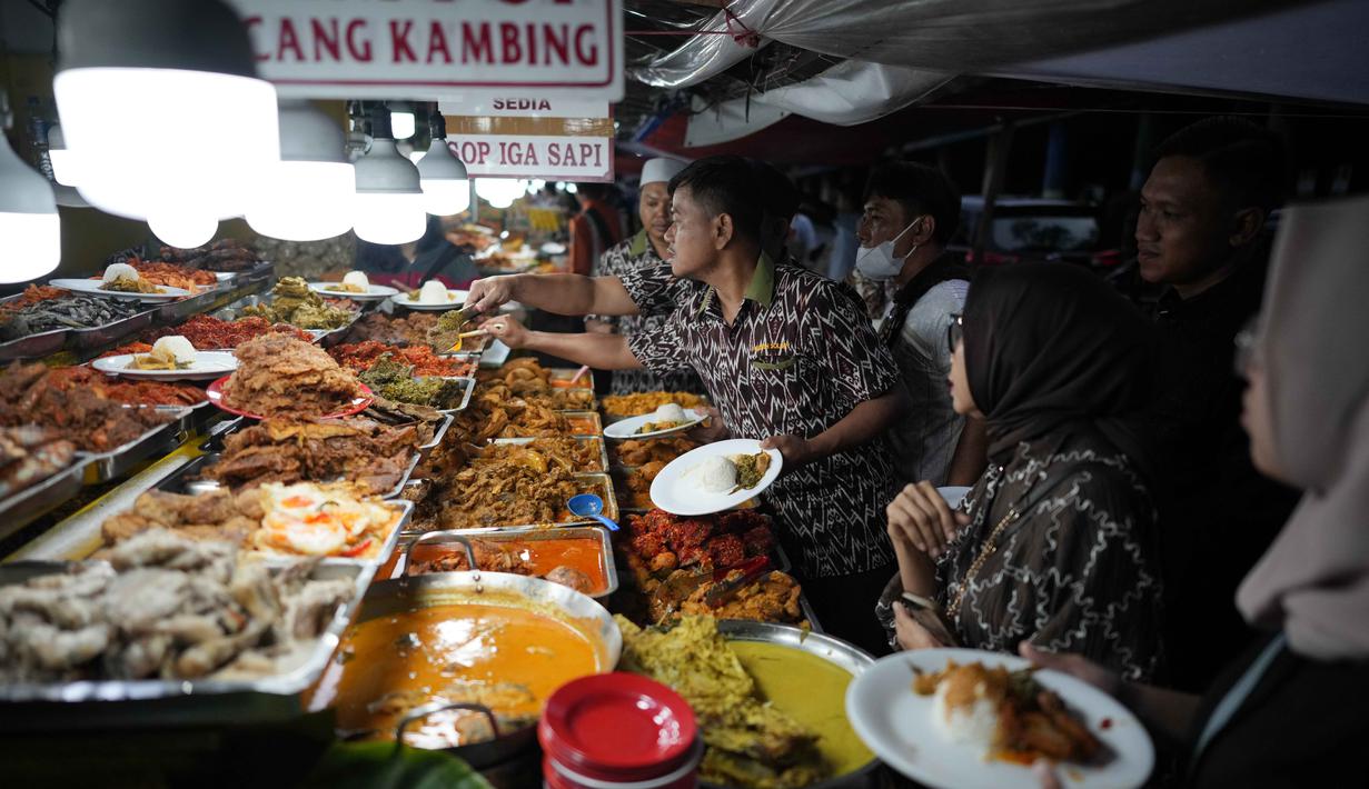 Para pekerja melayani pelanggan dengan hidangan untuk berbuka puasa pada hari kedua bulan suci Ramadan 1447 Hijriah, di sebuah warung makan, Jakarta, Jumat 20 Februari 2026. Setiap Ramadan, terutama ketika masuk waktu berbuka puasa, sentra kuliner Nasi Kapau di Jalan Kramat Raya, Senen, Jakarta Pusat, ramai dikunjungi masyarakat. (AP Photo/Dita Alangkara)