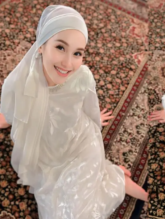 Ayu Ting Ting mengenakan gamis putih bercorak bunga dengan aksen beads di bagian kerah. Dipadukan kerudung putih model turban. [@ayutingting92]