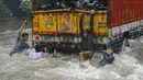 Sejumlah Pemuda India bergelantungan di truk saat melintasi banjir selama hujan deras di Mumbai (9/7). Mumbai dan daerah pinggiran lainnya telah mengalami hujan lebat semalaman yang mengakibatkan banjir. (AFP Photo/Punit Paranjpe)