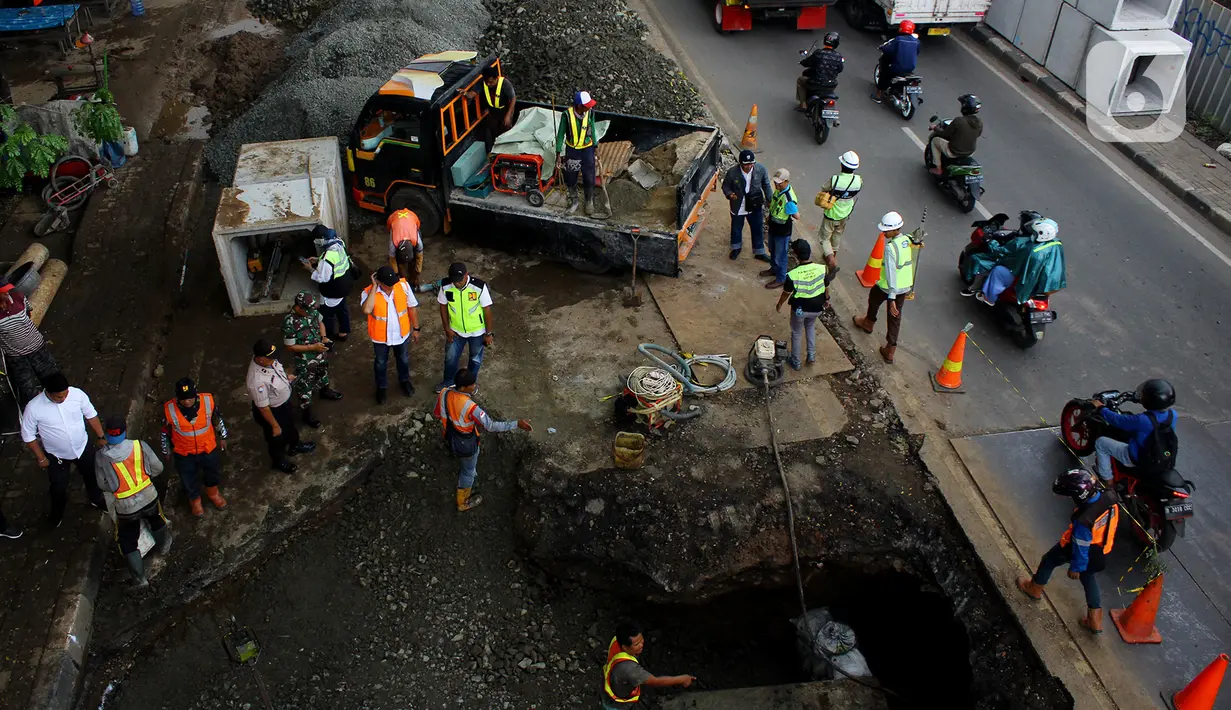 Pengendara melintas dekat perbaikan jalan ambles di Jalan Daan Mogot, Tangerang, Senin (13/1/2020). Amblesnya jalan penghubung ke Jakarta ini diduga karena adanya kebocoran pipa PDAM Tirta Kerta Raharja milik Pemkab Tangerang yang mengikis struktur tanah. (merdeka.com/Magang/Muhammad Fayyadh)