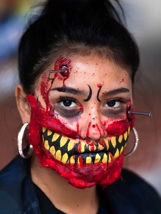 Seorang wanita berpartisipasi dalam Zombie Walk di Mexico City, Minggu (11/11). Dalam acara tahunan itu ratusan orang dengan penampilan yang seram serta mengenakan pakaian compang-camping berkumpul di pusat bersejarah ibu kota Meksiko. (AP/Claudio Cruz)