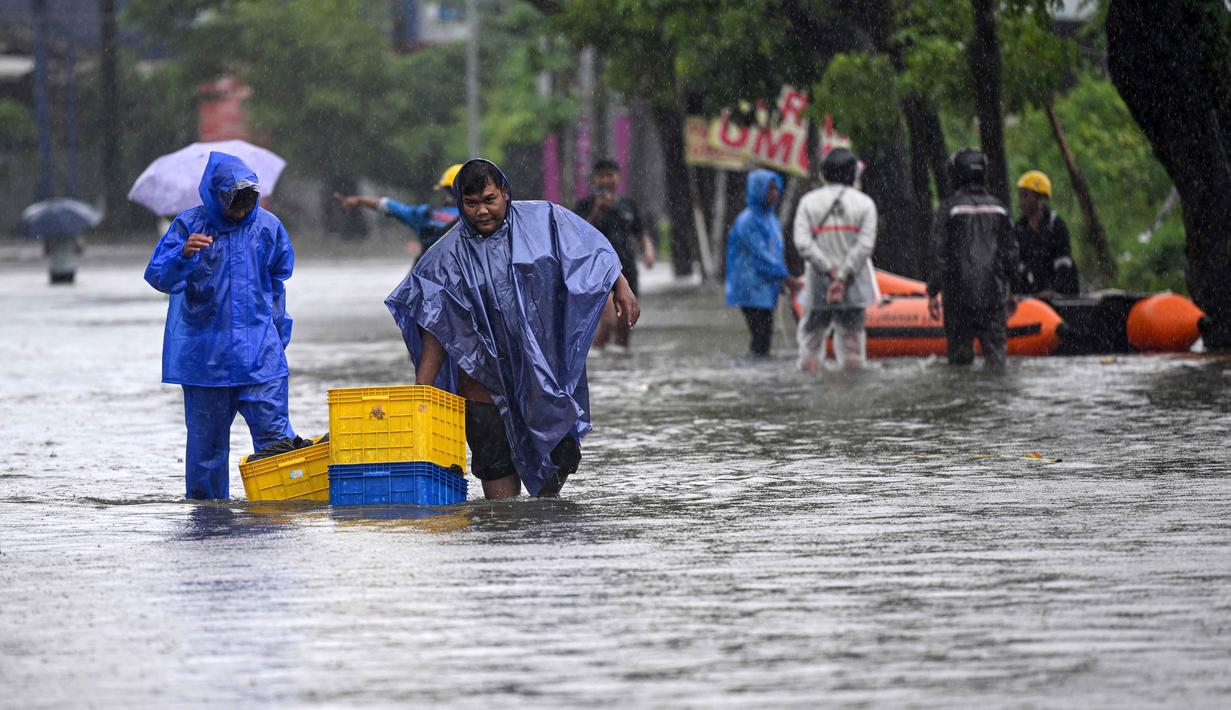 Hujan lebat yang mengguyur sejumlah wilayah di Bali, termasuk Kabupaten Badung dan Kota Denpasar, berimbas munculnya genangan air yang menutup sejumlah akses jalan utama. Tampak dalam foto, orang-orang memindahkan barang-barang mereka melalui air di jalan yang tergenang banjir akibat hujan lebat di Legian Kuta, Denpasar, Bali, pada Selasa 24 Februari 2026. (SONNY TUMBELAKA/AFP)