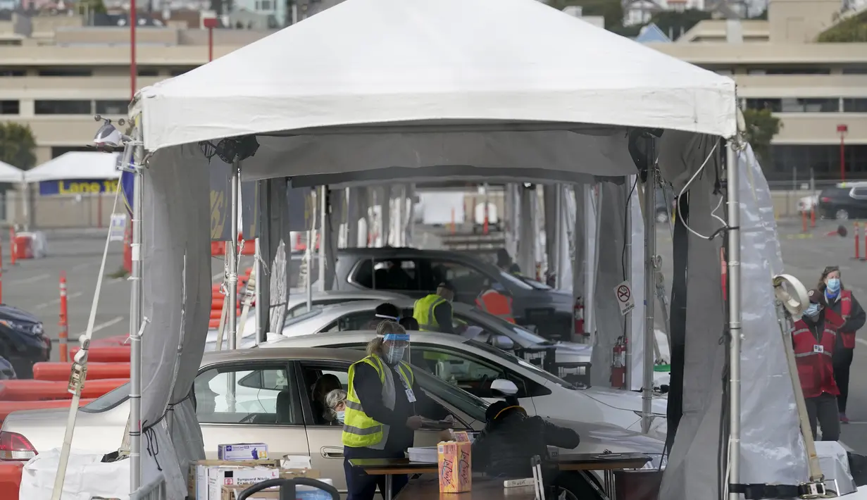 Petugas kesehatan menunggu di dalam mobil untuk vaksin COVID-19 di pusat vaksinasi drive-thru di City College of San Francisco di San Francisco, Senin (1/2). Ketika pasokan vaksin COVID-19 meningkat, UC San Francisco memperluas upaya vaksinasi kepada mereka yang paling berisiko. (AP Photo/Jeff Chiu)