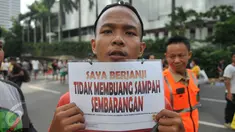 Seorang warga menunjukkan tulisan "Saya Berjanji Tidak Membuang Sampah Sembarangan" saat menjalani sidang karena tertangkap membuang sampah sembarangan di kawasan Bundaran HI, Jakarta, Minggu (24/4).(Liputan6.com/ Gempur M Surya)