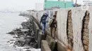 Warga sedang memancing di tanggul laut kawasan Muara Baru, Jakarta, Selasa (4/2/2025). (Liputan6.com/Herman Zakharia)