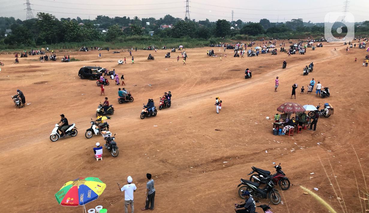 Warga menghabiskan waktu di tanah lapang kawasan Cipayung, Depok, Kamis (11/6/2020). Kurang tegasnya sanksi serta minimnya kesadaran masyarakat akan protokol kesehatan terkait covid-19 menyebabkan kawasan itu menjadi tempat berkerumun warga setiap sore hari. (Liputan6.com/Immanuel Antonius)