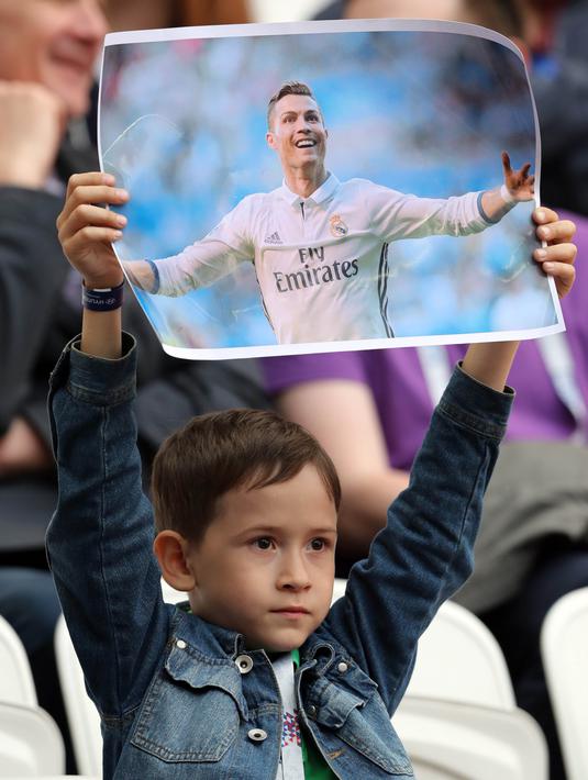 Seorang anak menunjukan poster bergambar bintang Real Madrid, Cristiano Ronaldo, sebelum laga Grup A Piala Konfederasi antara Portugal melawan Meksiko di Stadion Kazan Arena, Kazan, Minggu (18/6/2017). (EPA/Tolga Bozoglu)