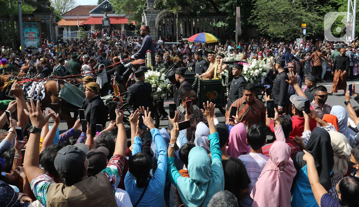 Pasangan pengantin Kaesang Pangarep dan Erina Gudono (tengah) menaiki kereta saat prosesi kirab Ngunduh Mantu di kawasan Selamet Riyadi, Solo, Jawa Tengah, Minggu (11/12/2022). Kirab ngunduh mantu pernikahan putra bungsu Presiden Joko Widodo, Kaesang Pangarep dan istrinya Erina Gudono yang dimulai dari Loji Gandrung menuju Pura Mangkunegaran tersebut disaksikan ribuan masyarakat Solo dan sekitarnya. (Liputan6.com/Herman Zakharia)
