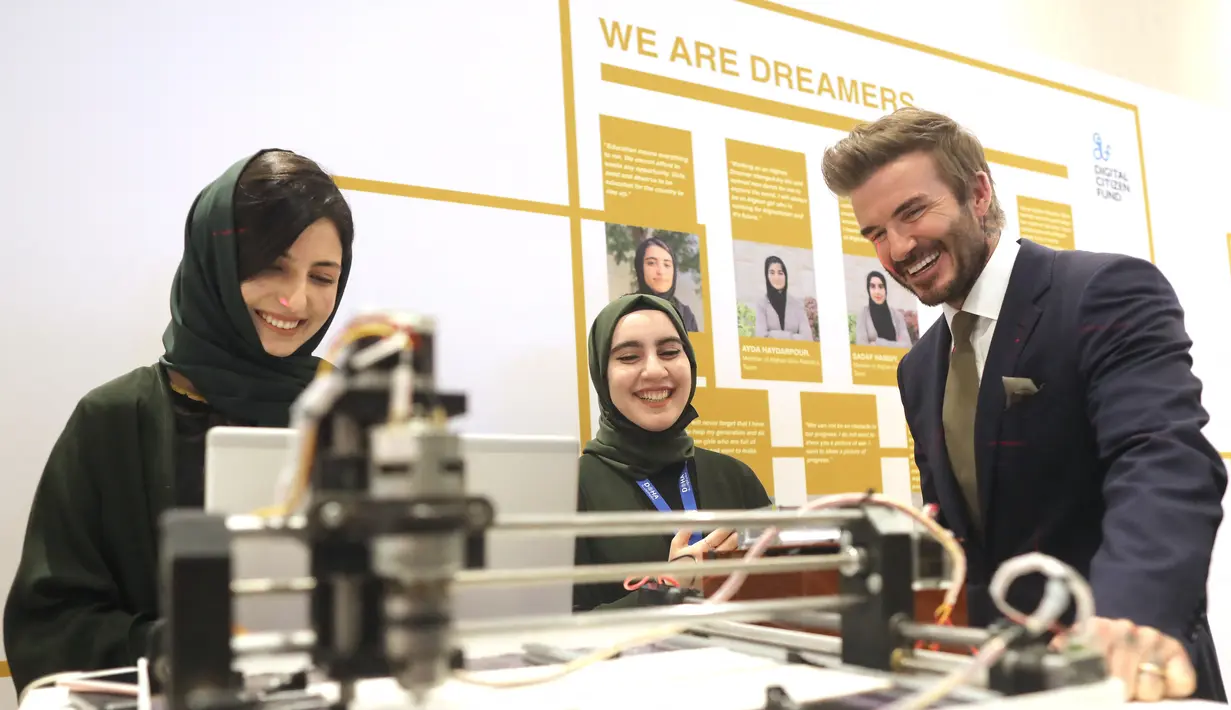 Mantan pemain sepak bola Inggris dan duta UNICEF, David Beckham bermain dengan robot yang dibuat oleh Tim Robotika Putri Afghanistan di Forum Doha di ibukota Qatar (27/3/2022). (Marwan Tahtah/Mofa/Doha Forum)
