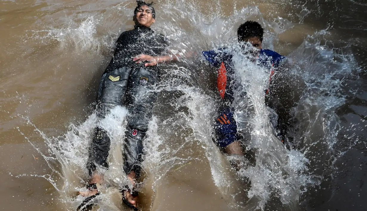Anak-anak muda mendinginkan diri dalam aliran kanal sungai saat suhu mencapai 40 derajat celsius di Lahore, Pakistan pada Rabu (27/5/2020). Banyak kota di Pakistan menghadapi kondisi gelombang panas dengan suhu mencapai 50 derajat celsius di beberapa tempat.  (Photo by Arif ALI / AFP)