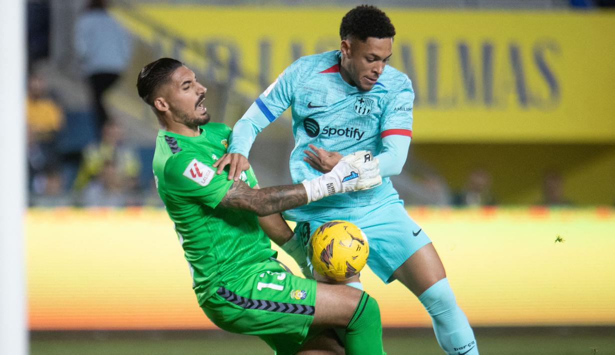 Pemain Barcelona, Vitor Roque (kanan) berusaha melewati penjagaan kiper Las Palmas, Alvaro Valles pada laga lanjutan Liga Spanyol 2023/2024 di Gran Canaria stadium, Las Palmas, Spanyol, Jumat (05/01/2024) dini hari WIB. Pemain 18 tahun itu mampu tampil impresif dengan membuat tiga shots, tertinggi dari semua pemain Barcleona. (AFP/Desiree Martin)
