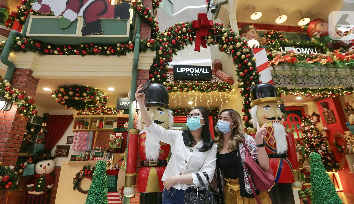 Pengunjung berswafoto berlatar belakang dekorasi Natal di atrium Lippo Mall Puri, Jakarta Barat, Sabtu (19/12/2020). Menyambut Hari Raya Natal dan Tahun Baru Lippo Mall Puri menampilkan dekorasi santa gift shop decoration dan santa home decoration. (Liputan6.com/Fery Pradolo)