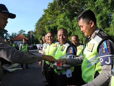 Petugas Polisi memberikan stiker bergambar bendera Indonesia dan Arab Saudi kepada rekannya selama persiapan menyambut kedatangan Raja Arab Saudi Salman bin Abdulaziz di Nusa Dua, Bali (2/3). (AFP Photo / Sonny Tumbelaka)