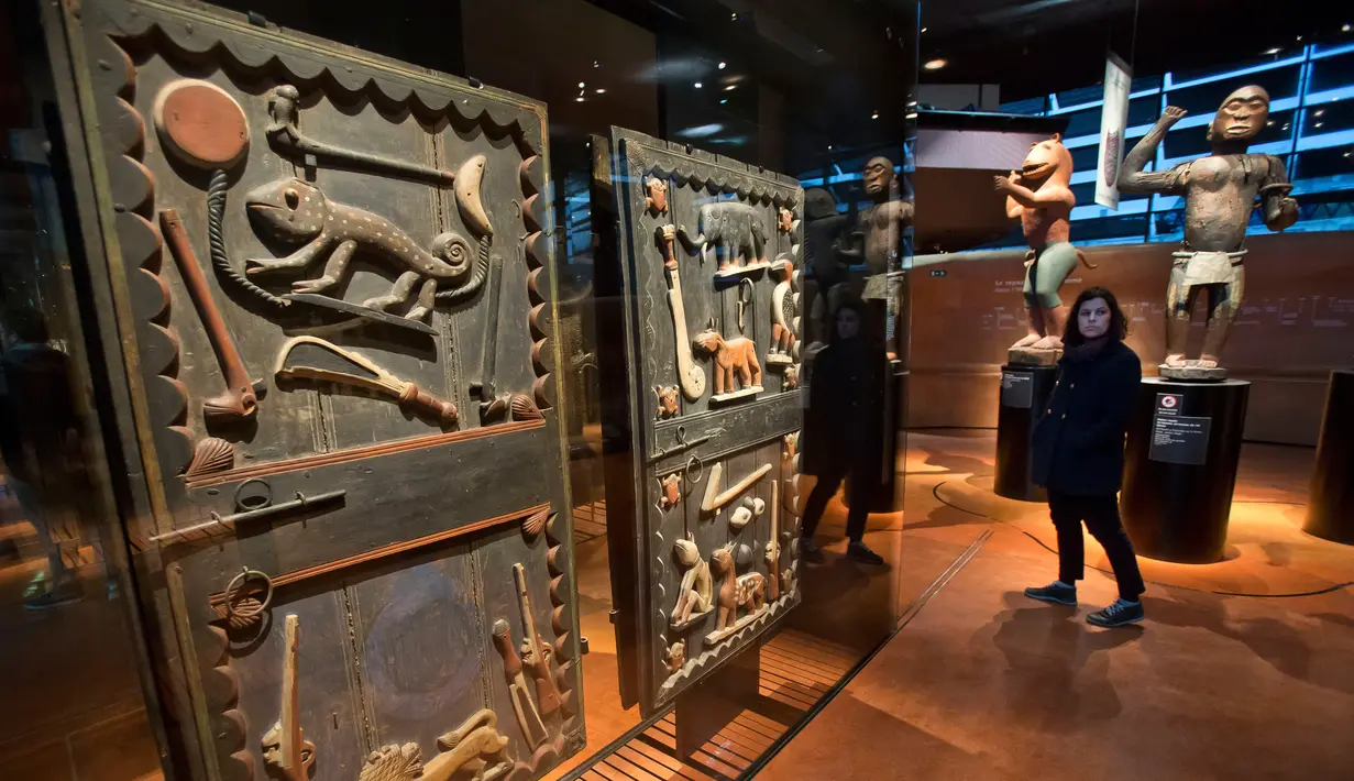 Pengunjung berjalan melewati sebuah pintu istana Raja Gele dari Kerajaan Dahomey di Museum Quai Branly, Paris, Prancis, Jumat (23/11). (AP Photo/Michel Euler)