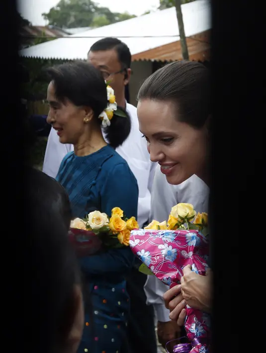 Angelina Jolie dalam kunjungan kemanusiaannya sebagai duta UNHCR terlihat bersama pemimpin oposisi Myanmar, Aung San Suu Kyi, menerima bunga dari pekerja pabrik di asrama perempuan kota HlaingTharYar di Yangon, Myanmar, (1/8/2015). (Bintang/EPA)