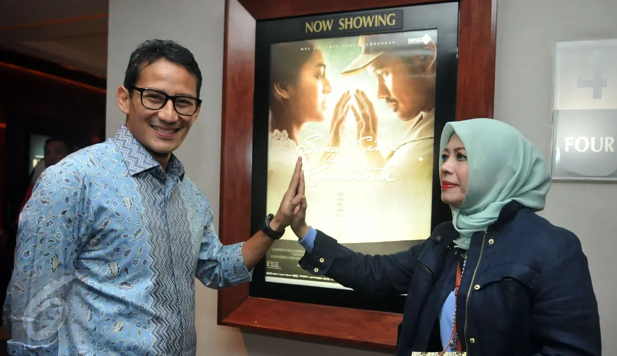 Sandiaga Uno dan istri berpose dekat  poster film "Surat Cinta Untuk Kartini" di XXI Senayan City, Selasa Malam (24/5/2016). Bakal Calon Gubernur DKI Jakarta itu mengaku mendukung perfilman Indonesia dan industri kreatif. (Liputan6.com/Johan Tallo)