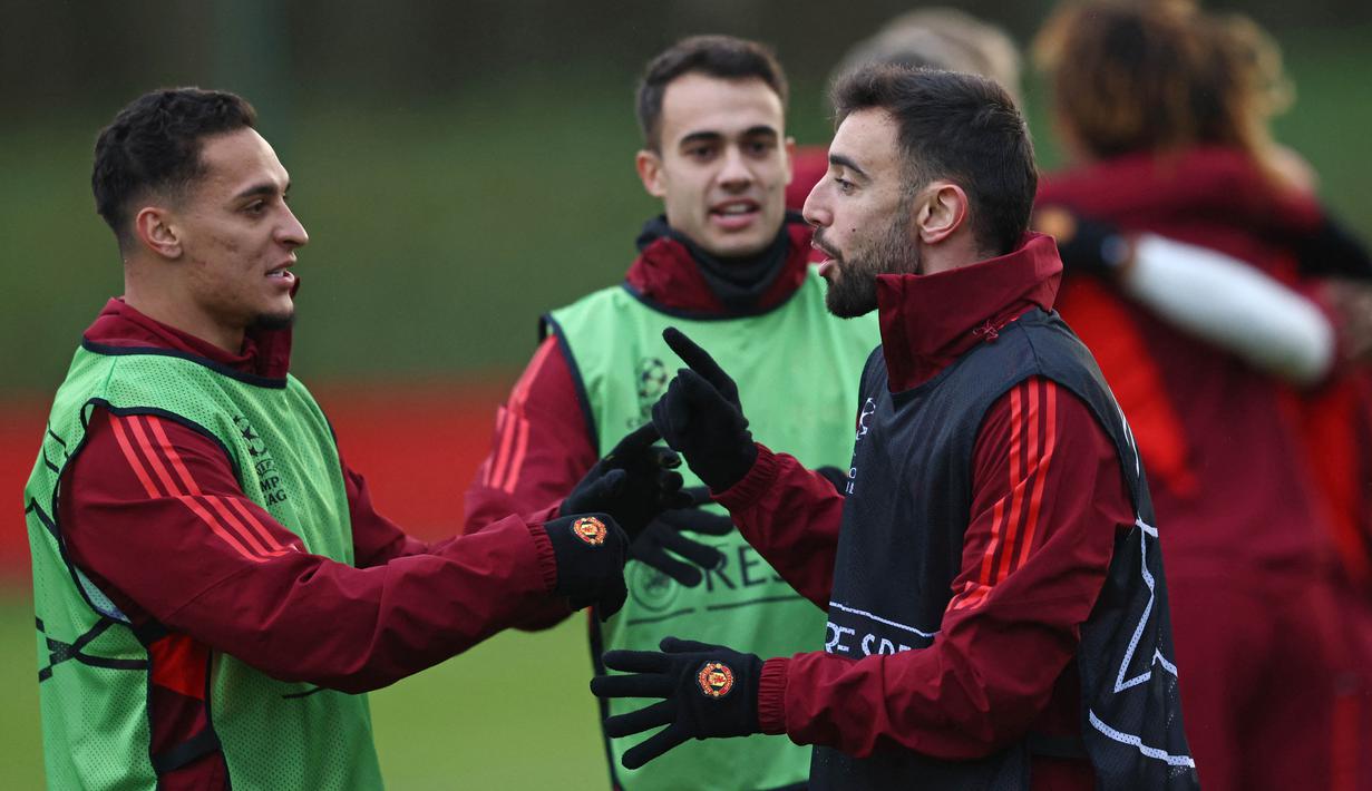 Pemain MU, Anthony (kiri) bercengkrama dengan Bruno Fernandes, dalam sesi latihan yang berlangsung di Carrington, Manchester, Selasa (12/12/2023) dini hari WIB. (AFP/Darren Staples)