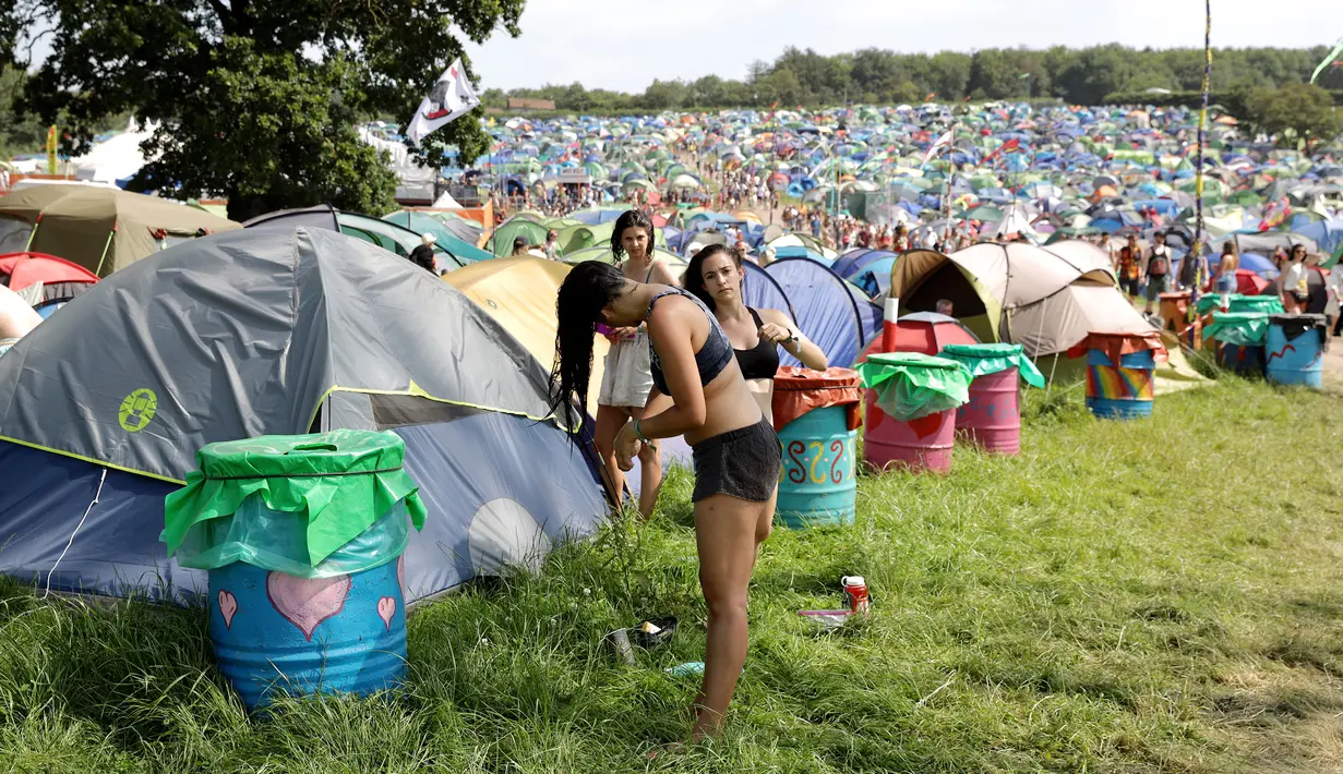 Seorang wanita mencuci rambutnya selama hari keempat Festival Glastonbury di Worthy Farm, Somerset, Inggris (29/6/2019). Gelombang panas yang melanada bagian-bagian Eropa tidak menyurutkan pengunjung untuk berkumpul di festival ini. (AP Photo/Grant Pollard)
