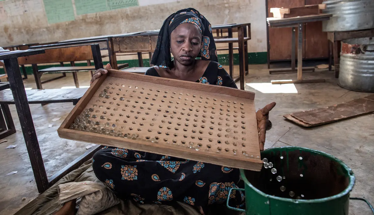 Seorang petugas menghitung kelereng yang akan digunakan untuk pemilihan Presiden Gambia di distrik Tallinding, Serekunda, Gambia (30/11). Kelereng ini digunakan untuk memilih presiden dan sebagai pengganti kertas suara dalam pemilu. (AFP/Marco Longari)
