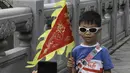 Seorang anak memegang bendera untuk difoto saat mengikuti lomba perahu naga di kawasan bersejarah Teluk Lychee di Guangzhou, Provinsi Guangdong, China selatan, Jumat, 3 Juni 2022. Perlombaan perahu naga kembali digelar di beberapa bagian China untuk pertama kalinya sejak merebaknya pandemi pada akhir 2019, saat pembatasan dicabut bersama dengan penurunan besar  kasus COVID-19. (AP Photo/Caroline Chen)