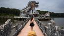 Foto pada 27 April 2019 memperlihatkan pengunjung berpose di depan bangunan berbentuk naga di Taman Air Ho Thuy Tien yang telah lama ditinggalkan di kota Hue, Vietnam. Taman air Ho Thuy Tien pertama kali dibuka untuk umum dalam keadaan setengah selesai pada tahun 2004. (Manan VATSYAYANA/AFP)
