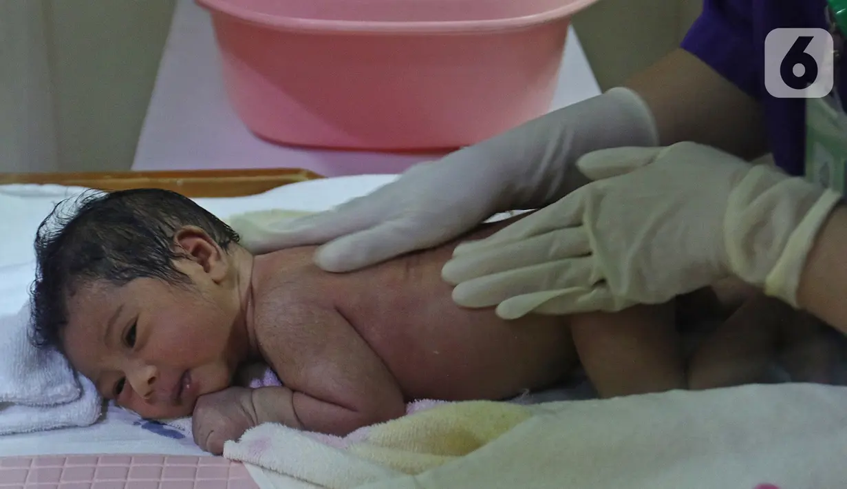 Perawat saat mempraktekan cara memandikan bayi kepada seorang ibu di RSIA Tambak, Jakarta, Kamis (18/02/2021). Melatih para ibu baru untuk memandikan bayi pertama tersebut dilakukan dengan menerapkan protokol kesehatan ketat. (Liputan6.com/Herman Zakharia)