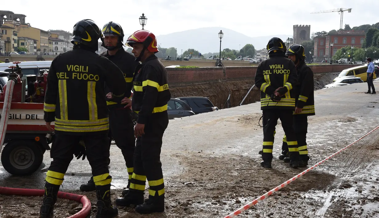 Petugas pemadam kebakaran berjaga di lokasi jalanan yang ambles di dekat sungai Arno di Lungarno Torrigiani, Florence, Italia (25/5). Kejadian tersebut disebabkan oleh pecahnya pipa besar saluran air. (AFP PHOTO/CLAUDIO GIOVANNINI)