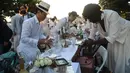 Para peserta dalam balutan serba putih  berkumpul untuk Dinner en Blanc atau "makan malam putih" di Tuileries Gardens, Paris, Kamis (6/6/2019). Saat acara, baik pria maupun wanita tampil gaya dengan topi mewah, mantilla, bulu dan gaun berenda. (Lucas BARIOULET/AFP)