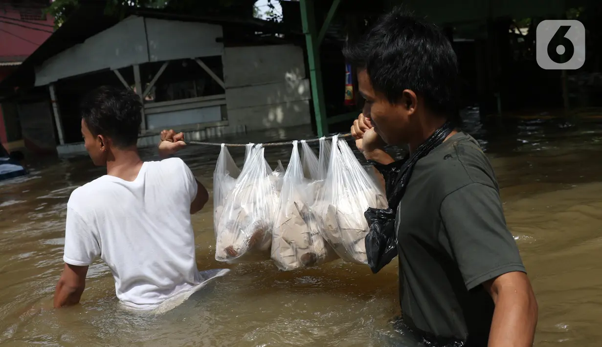 Warga membawa makanan saat melintasi banjir yang merendam perumahan Ciledug Indah, Tangerang, Banten, Kamis (2/1/2020). Memasuki hari kedua, kondisi perumahan tersebut masih tergenang banjir setinggi dada orang dewasa. (Liputan6.com/Angga Yuniar)