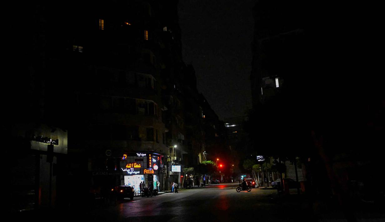 Warga berdiri di depan toko-toko yang tutup lebih awal karena pemberlakuan jam malam yang diperintahkan pemerintah untuk mengurangi biaya energi di pusat kota Kairo, Mesir, pada Kamis 2 April 2026. Pemerintah Mesir memberlakukan pembatasan jam operasional bagi berbagai sektor bisnis sebagai langkah darurat untuk mengatasi krisis energi. (Khaled DESOUKI/AFP)
