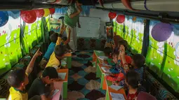 Anak-anak Suriah mengikuti pelajaran di dalam bus yang dikonversi menjadi ruang kelas di desa Hazano di barat laut Suriah (15/9/2019). Pelajaran di kelas bus ini yaitu bahasa Arab, matematika, sains, dan kadang-kadang bahasa Inggris , serta menyanyi dan menggambar. (AFP Photo/Aaref Watad)