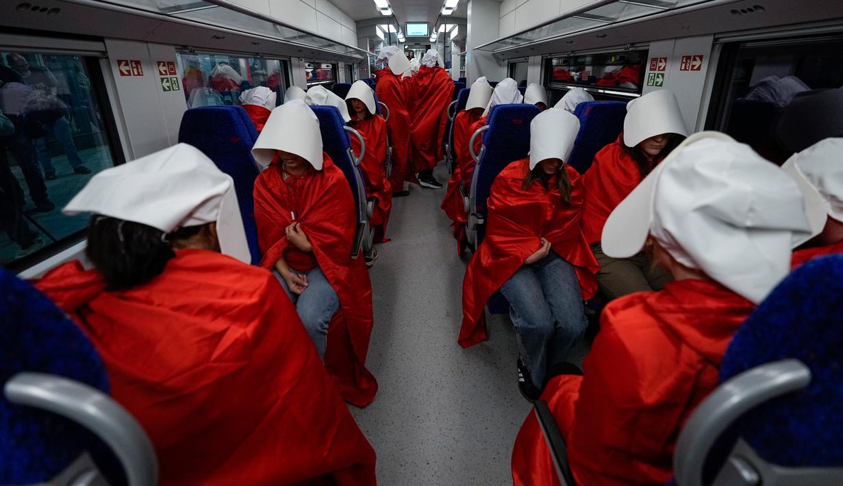 Pengunjuk rasa yang mendukung hak-hak perempuan berpakaian seperti karakter dari serial TV "The Handmaid's Tale" saat melakukan perjalanan untuk memprotes rencana pemerintah baru Perdana Menteri Benjamin Netanyahu untuk merombak sistem peradilan di sebuah stasiun kereta api di Yerusalem, Israel, 1 Maret 2023. Mengacu pada fenomena yang berkembang, harian Inggris The Guardian menggambarkan penampilan para pelayan sebagai salah satu simbol paling kuat dari protes feminis kontemporer. (AP Photo/Ohad Zwigenberg)