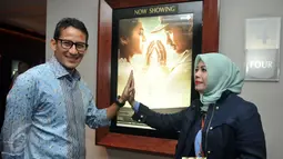 Sandiaga Uno dan istri berpose dekat  poster film "Surat Cinta Untuk Kartini" di XXI Senayan City, Selasa Malam (24/5/2016). Bakal Calon Gubernur DKI Jakarta itu mengaku mendukung perfilman Indonesia dan industri kreatif. (Liputan6.com/Johan Tallo)
