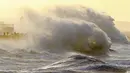 Ombak menghantam tembok laut saat Badai Eunice membawa angin kencang di Porthcawl, Wales, Inggris (18/2/2022). Inggris menempatkan tentara dalam keadaan siaga dan sekolah-sekolah ditutup ketika prakiraan cuaca mengeluarkan dua peringatan "cuaca merah". (AFP/Geoff Caddick)