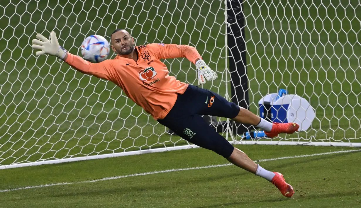 Kiper Brasil, Weverton berusaha menghalau bola saat mengambil bagian dalam sesi latihan di Stadion Al Arabi SC di Doha (6/12/2022). Brasil akan bertanding melawan Kroasia pada babak perempatfinal Piala Dunia 2022 Qatar di Education City Stadium, Doha pada Jumat (9/12) pukul 22.00 WIB mendatang. (AFP/Nelson Almedia)