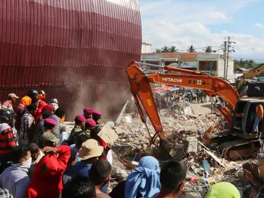 Eskavator membantu mengangkat puing bangunan yang runtuh akibat gempa di Pasar Meureudu, Pidie Jaya, Aceh, Kamis (8/12). Dikabarkan korban meninggal sudah mencapai 102 orang. (Liputan6.com/Angga Yuniar)