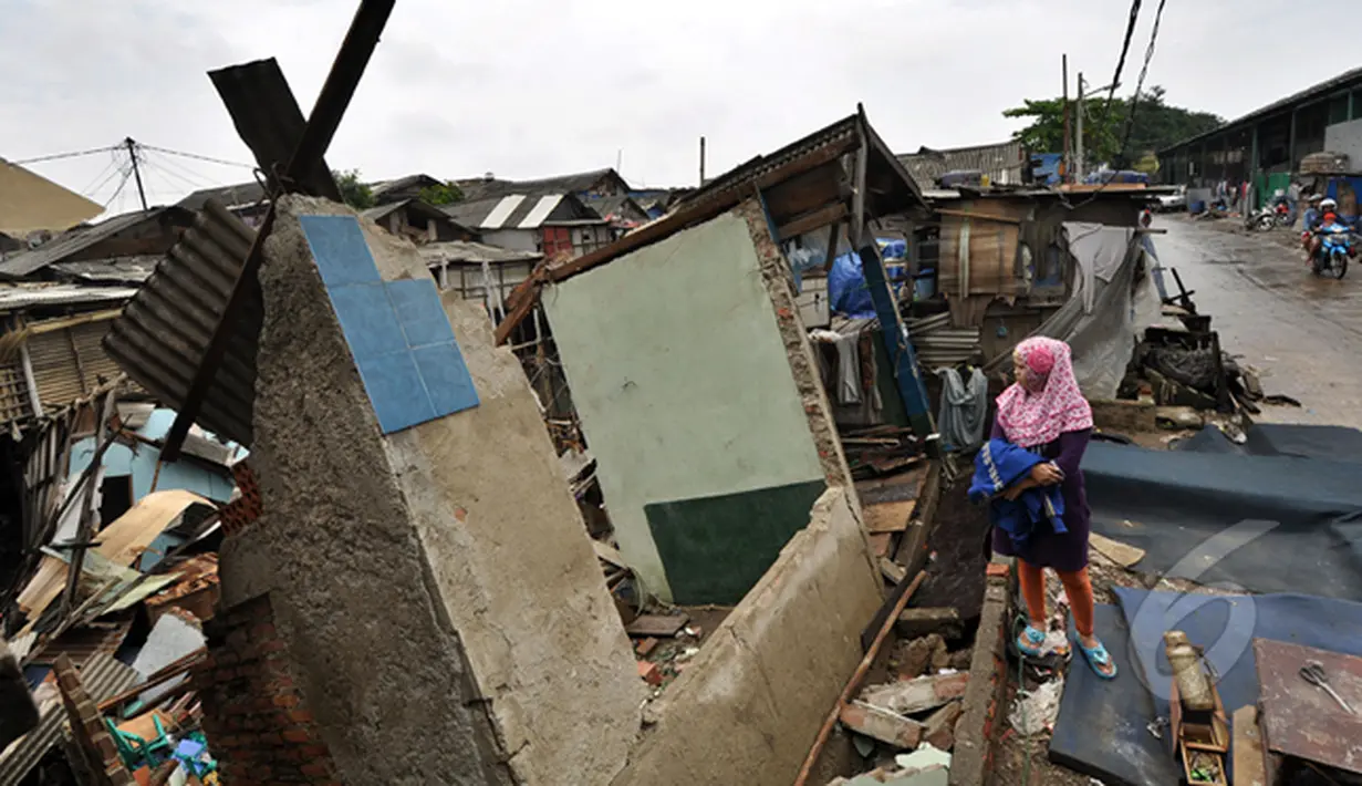 Seorang perempuan melihat kondisi rumah yang rubuh dikawasan muara baru, Jakarta, Jumat (13/2/2015).  Sebanyak 33 rumah di muara baru Jakarta Utara mengalami kemiringan parah dan 2 buah rumah ambruk akibat banjir. (Liputan6.com/Faizal Fanani)