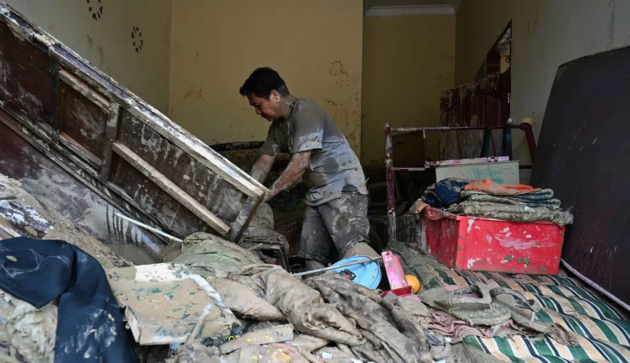 Desa Garoga dilaporkan "hilang" dan berganti menjadi hamparan lumpur, batu, serta sampah potongan dan batang kayu pohon. Tampak dalam foto, seorang warga mengumpulkan barang-barangnya dari rumahnya yang rusak akibat banjir bandang di Garoga, Provinsi Sumatera Utara, pada Kamis 4 Desember 2025. (YT HARIONO/AFP)