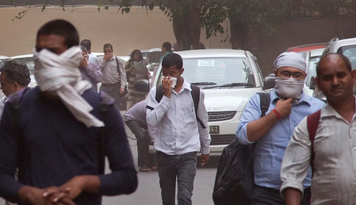 Warga beraktivitas dengan memakai penutup hidung saat badai debu menyelimuti New Delhi, India, Rabu (2/5). Badai pasir yang menerjang wilayah utara India ini telah menewaskan 77 orang. (AP Photo/Manish Swarup)