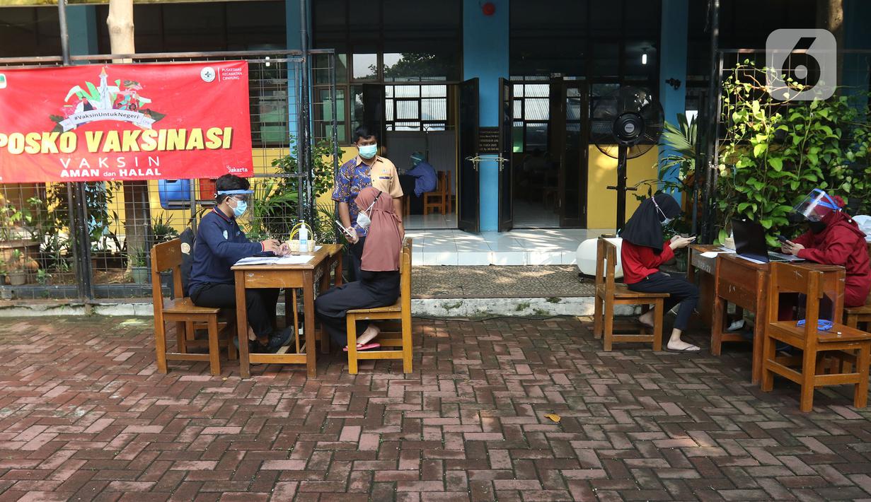 Tenaga kesehatan mendata waraga sebelum divaksin di MTs As-Syafiiyah, Cilangkap, Jakarta, Kamis (3/6/2021). Vaksinasi massal di zona merah RT 03/RW 03 Cilangkap akibat klaster halal bi halal dilakukan terhadap warga yang telah menjalani tes usap dengan hasil negatif. (Liputan6.com/Herman Zakharia)