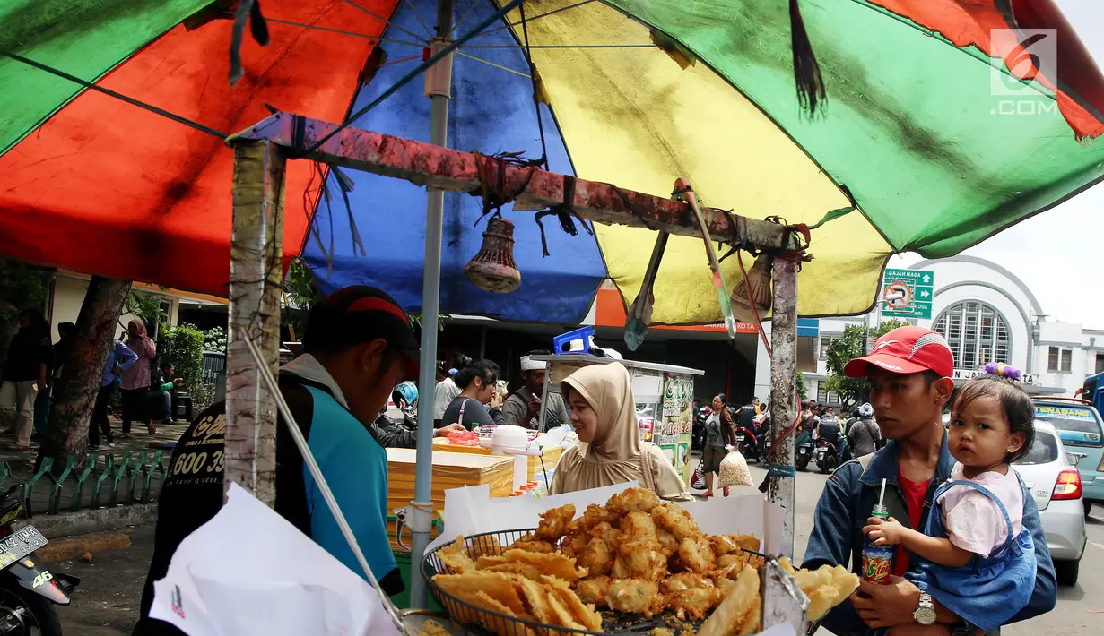 Warga membeli gorengan di di kawasan Kota Tua, Jakarta Selasa (2/1). Meski ada larangan berdagang di kawasan tersebut, pedagang tetap nekat berjualan. (Liputan6.com/Johan Tallo)