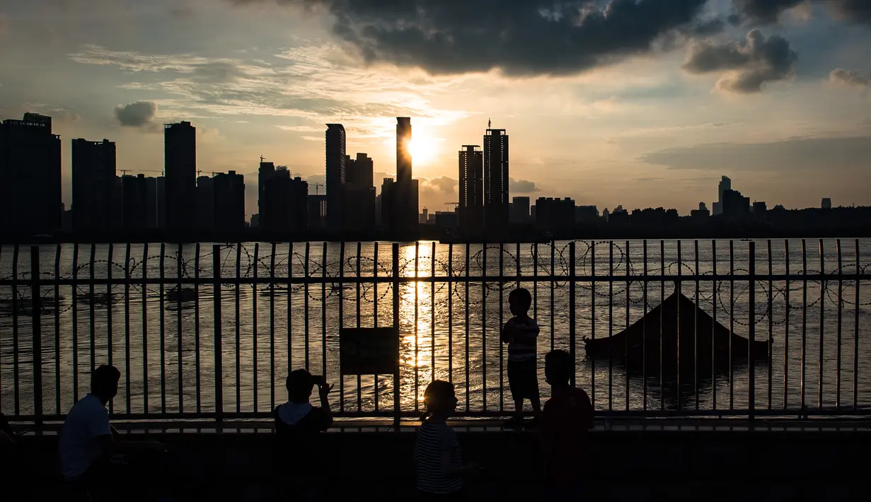 Seorang pejalan kaki memotret lokasi terendamnya sebuah paviliun akibat meningkatnya ketinggian air di Sungai Yangtze di Wuhan, Provinsi Hubei, China tengah (13/7/2020). (Xinhua/Xiao Yijiu)