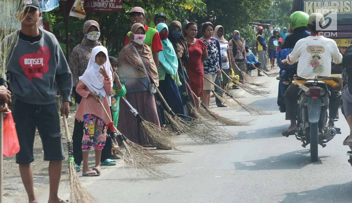 Sejumlah penyapu koin kali Sewo menunggu di sepanjang pinggir jalan, Subang, Jawa Barat, Sabtu (7/1). Mereka menunggu pengendara yang lewat melempar koin ke jalan. (Liputan6.com/Helmi Afandi)